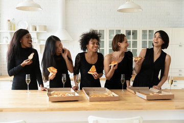 Five gorgeous overjoyed multi-ethnic best friends elegant women in black cocktail dresses eating...
