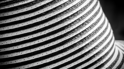 Handcrafted hat with black and white bands, crisscross lines, close-up under sun light