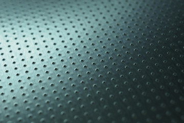 Dark industrial metallic background. Tinted blue-green wallpaper. Perforated aluminum surface with many holes. Perforation rows go into the distance and form a perspective. Macro