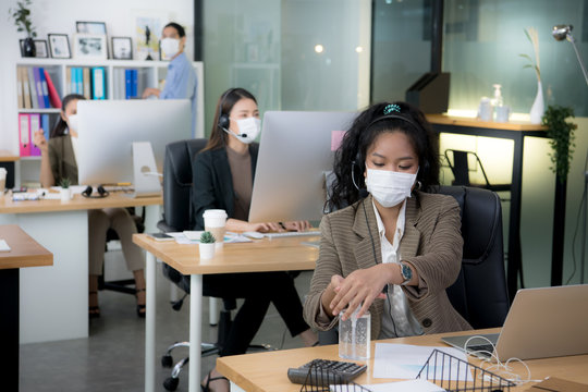 Asian woman office worker wearing face mask working in new normal office and doing social distancing during corona virus covid-19 pandemic