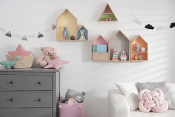 Cute children's room with house shaped shelves, sofa and chest of drawers. Interior design