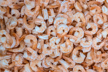 Raw peeled frozen shrimps. Showcase in a supermarket. Top view, background. Selective focus. Blurred.