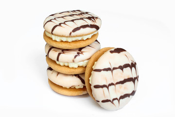 Delicious cream cakes isolated on white background. Sandwich cookies covered with chocolate
