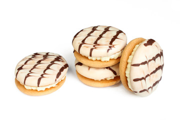 Delicious cream cakes isolated on white background. Sandwich cookies covered with chocolate
