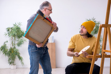 Young man taking lesson from old painter