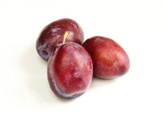 Three fresh plums isolated on white background. Tasty organic fruit