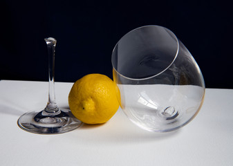 still life with broken glass goblet and yellow lemon on dark background