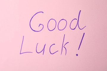 Phrase GOOD LUCK on pink background, top view