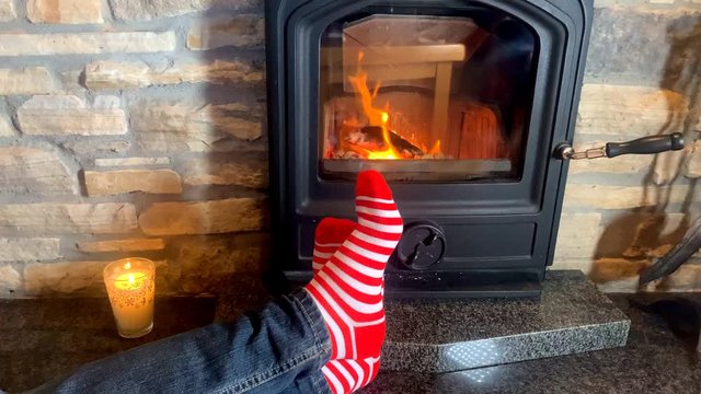 man lies near a hot burning fireplace, legs stretched out in red striped socks to the fire, christmas concept