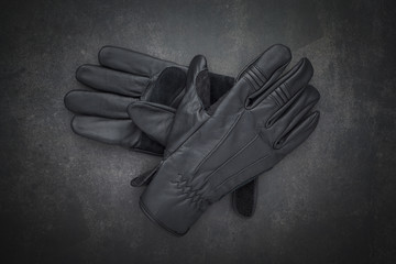 top view shot a pair of new black leather motorcycle gloves classic style for protect biker hands on dark gray, grey, black tone texture background with copy space for text