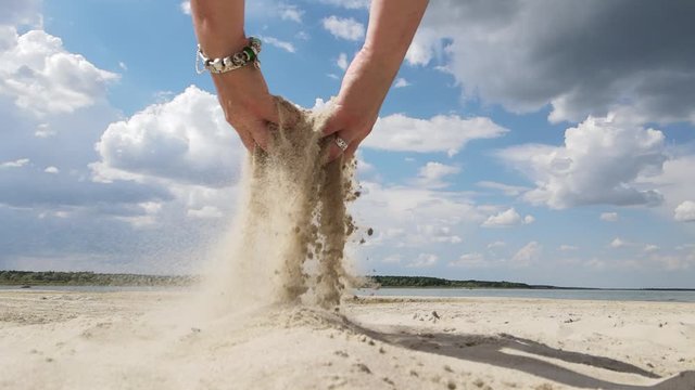Video, female hands scatter white sand on the beach on a sunny hot day