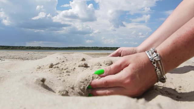Video, female hands scatter white sand on the beach on a sunny hot day