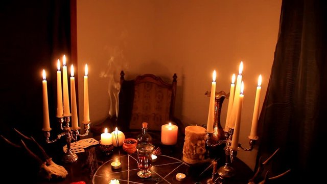 in a dark room on a round esoteric table candles are burning, animal skulls are lying, a pentagram is drawn, a model of a red heart, candles, a concept of magic, witchcraft