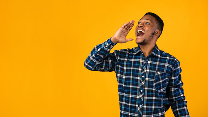 Positive Black Man Shouting Holding Hand Near Mouth, Yellow Background