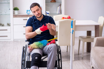 Young leg injured contractor in wheel-chair cleaning the house