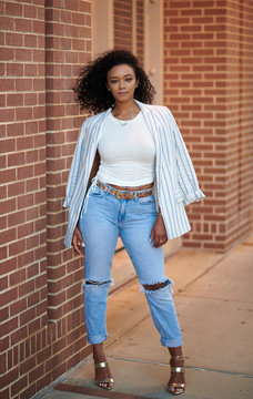 Premium Photo  Sleek and chic a young black woman poses in a fashionable  white tshirt and black pants with a modern grey building in the background