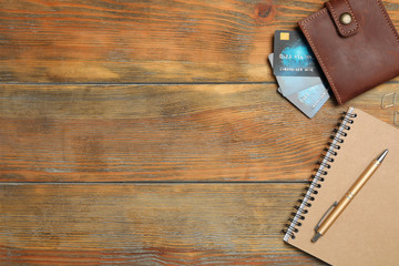 Stationery and wallet with credit cards on wooden background, flat lay. Space for text
