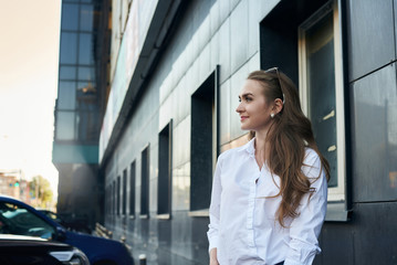 Summer sunny lifestyle fashion portrait of young stylish woman walking on street, wearing cute trendy outfit. Girl with long hair and natural makeup