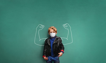 Child wearing a breathing mask  because of the virus in school, in front of blackboard with muscles...