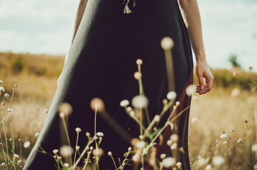 Mid section portrait boho style dress young woman standing in the grass and wildflowers connecting with nature. Concept: spirituality, zen, balance, equilibrium, mindfulness © Cristina