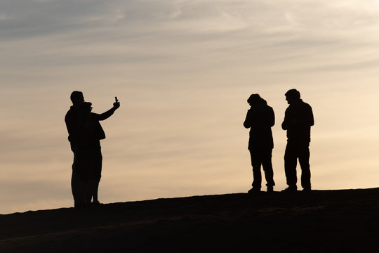 Silhouettes of tourists taking pictures at sunset in the Sahara desert Morocco