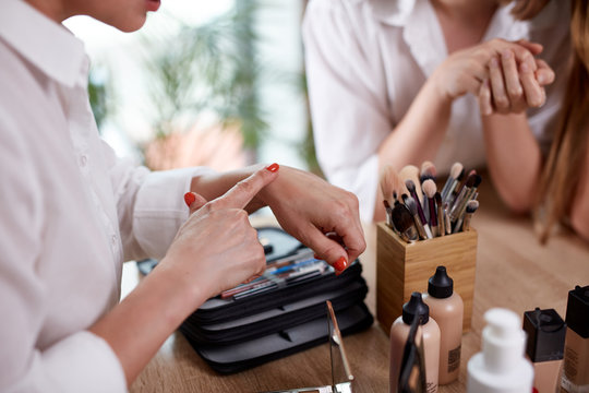 professional make-up artist shows master class to students, she is applying decorative cosmetics on hands, in beauty salon
