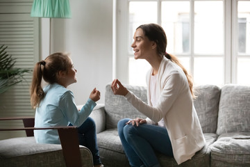 Side view adorable small preschool girl involved in speaking lesson with professional mixed race...