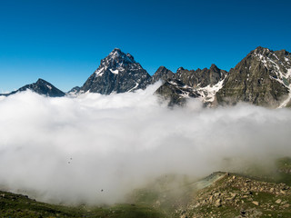 Mountain landscape on the Alps, rocky mountains at high altitude, moody sky green valley and hiking paths for tourism summer vacation