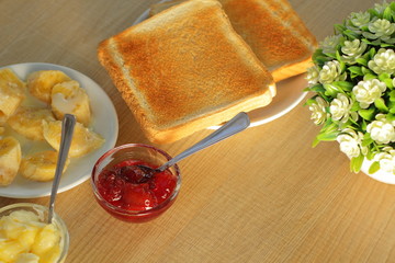breakfast bread toast with butter, jam, coffee on table, morning light, early time for meal 