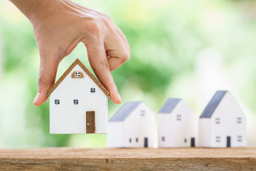 A woman shopping for a new home is hand hold at one of the houses on the table in the backyard, Saving money or loan for business Investment real estate concept.