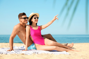 Fototapeta premium Happy couple resting on sunny beach at resort