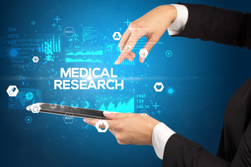 Close-up of a touchscreen with MEDICAL RESEARCH inscription, medical concept