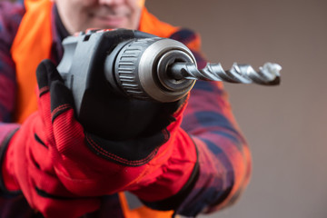Driller. Man brings a electric drill to the camera. Worker wants to drill a camera. Concept - man...