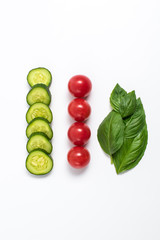 Creative mockup of tomato slices, cucumber and basil leaves. Flat lay, top view. Food concept. Vegetables isolated on a white background.