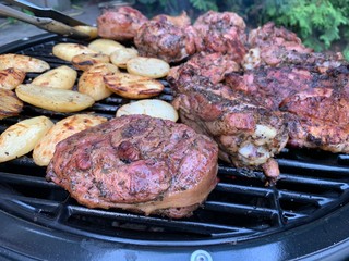 Fried chicken steak. A picnic in nature, poultry is cooked on a fire. Grilled meat dish with smoke. Outdoor cooking.