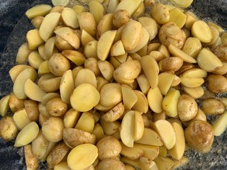 Fried potatoes over a fire. Picnic in nature, food is prepared on the fire. Grilled young potatoes with smoke. Outdoor cooking.