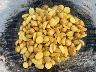 Fried potatoes over a fire. Picnic in nature, food is prepared on the fire. Grilled young potatoes with smoke. Outdoor cooking.