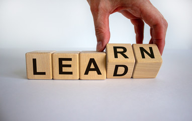 Hand is turning a cubes and changes the word 'learn' to 'lead' or vice versa. Beautiful white...