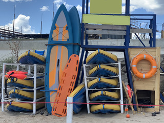 Surfboards are stacked on the shore. Beach equipment near the rescue station. Rubber boats and...