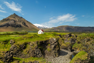 Small white house in Iceland and a Stapafell, a volcanic mountain on the south side of...