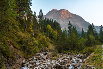 Obraz premium Sunset in Austria, State Vorarlberg with the mountain Widderstein in the background and a stream in the foreground.
