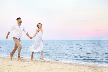 Fototapeta na wymiar Happy couple having romantic walk on beach. Space for text
