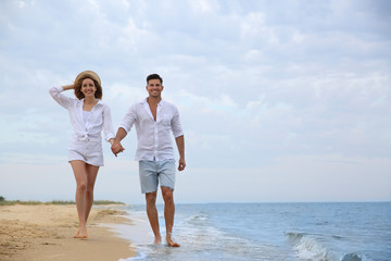 Happy couple having romantic walk on beach. Space for text