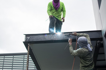  worker  welds the steel structure of the roof at the construction site.