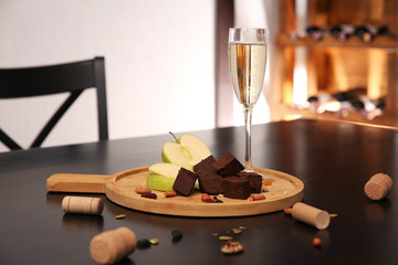 Delicious brunost cheese, apple and glass of champagne on table