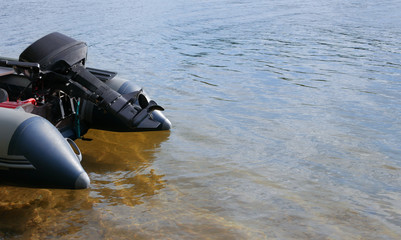 Pvc inflatable boat with a motor on the water near the shore. Copy space