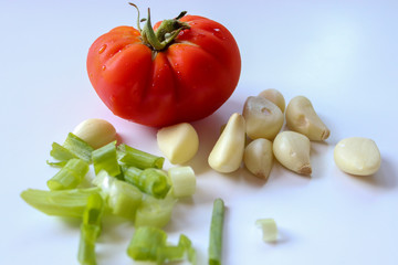 Close-up of ripe tomato and garlic cloves with white background