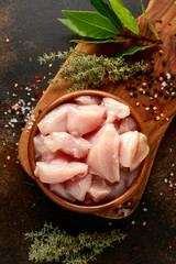 Raw Diced chicken breast meat in wooden bowl ready to cook with seasonings