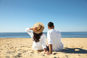 Young couple on beach near sea, back view. Honeymoon trip