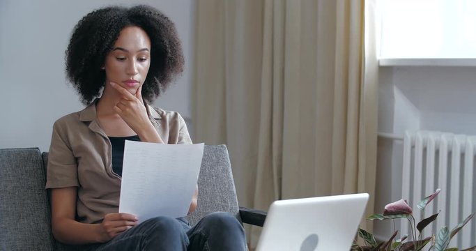 Young woried curly African girl receives letter in mail with bad news, medical tests, learns about failed exams, holds refusal notice in her hands, feels sad displeasure resentment, upset female face
